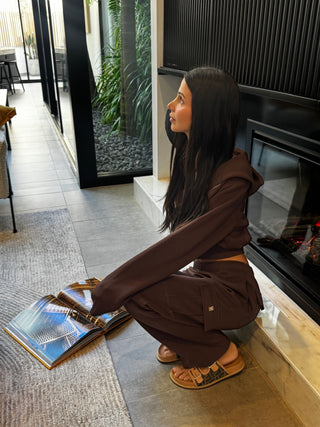 Model sitting in INTIMISSY Espresso Studio plush cargo pants styled for everyday streetwear